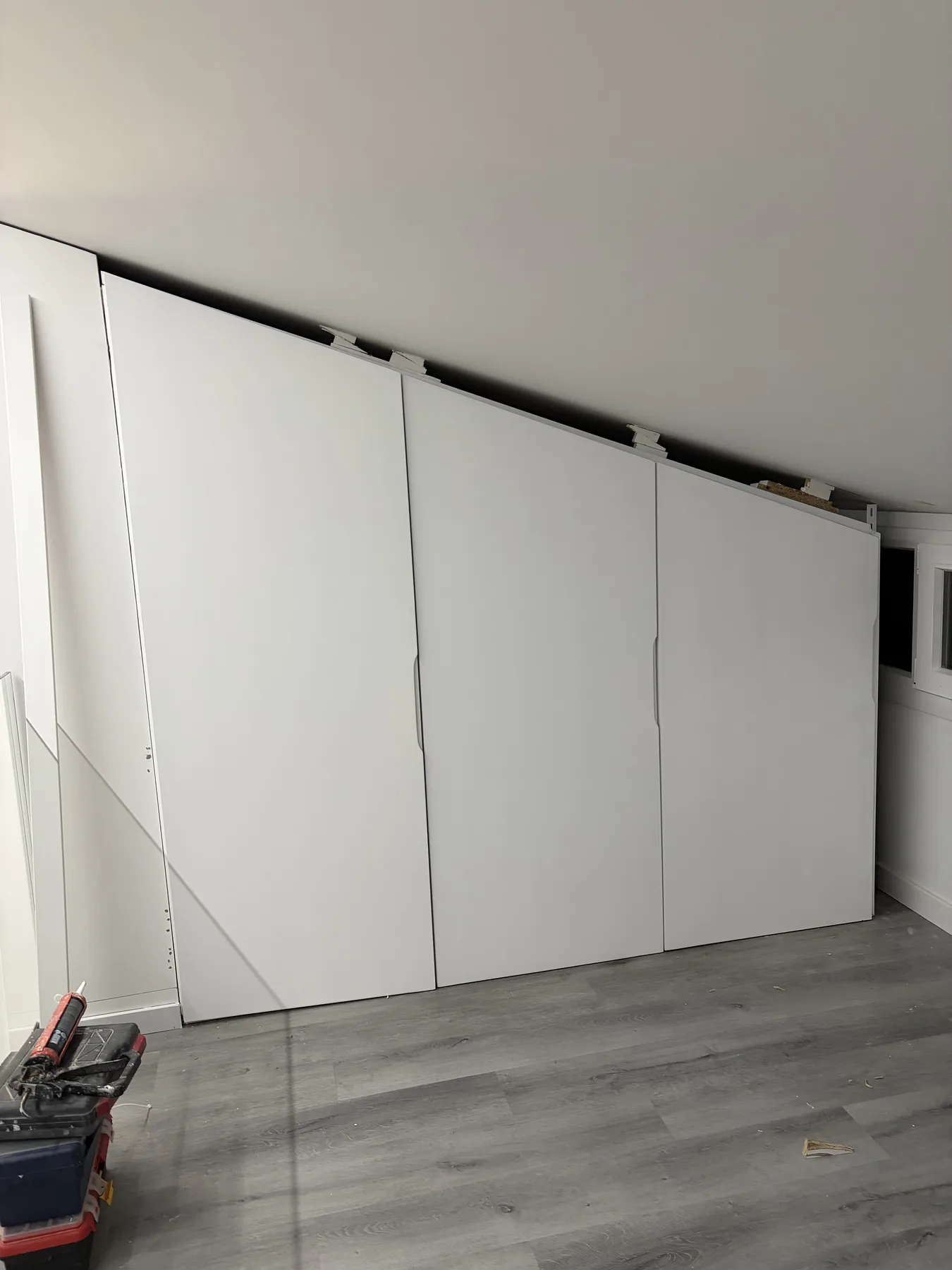 Armario blanco de puertas correderas adaptado a un techo inclinado
