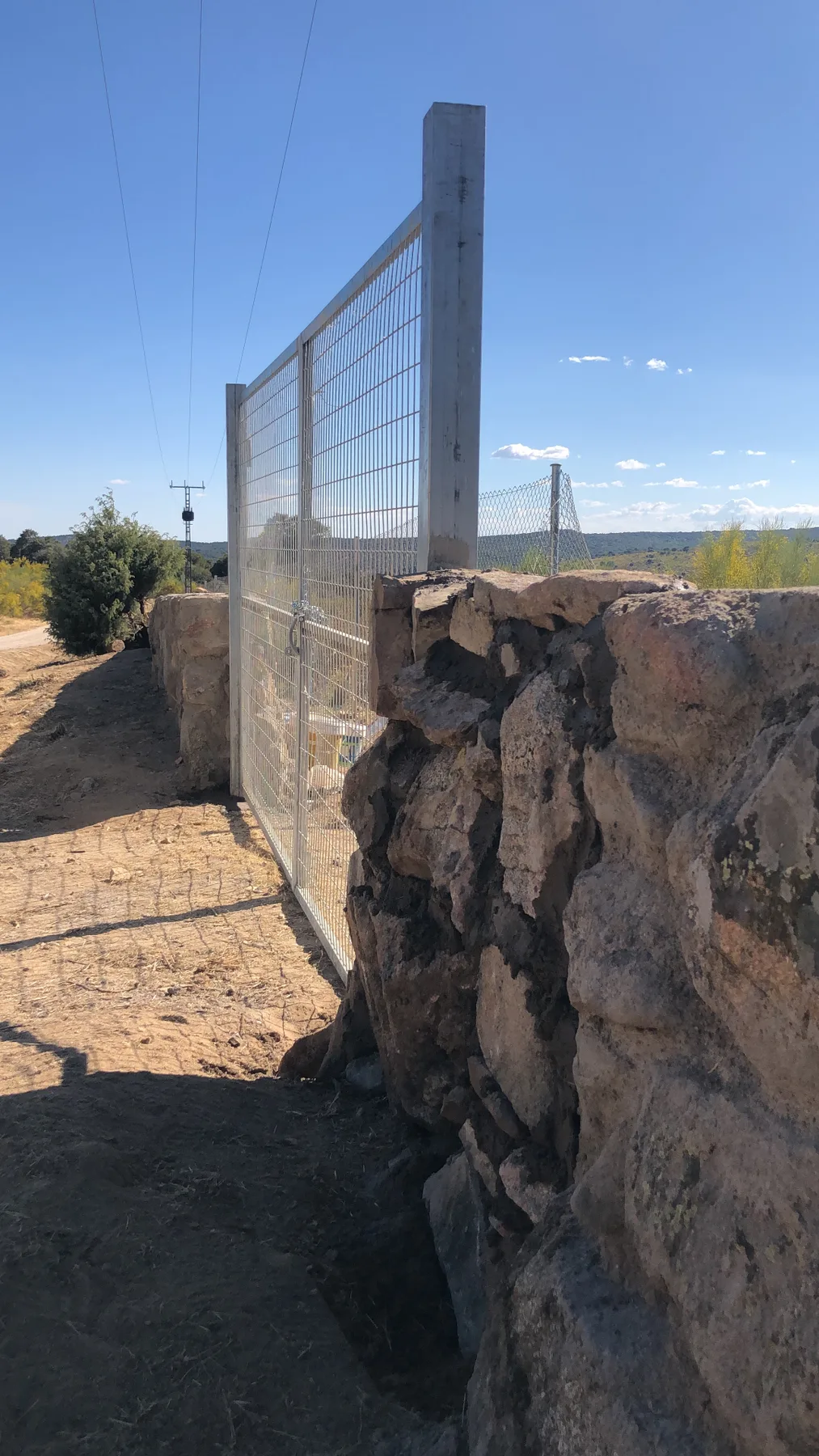 Cerramiento metálico galvanizado integrado en un muro de piedra