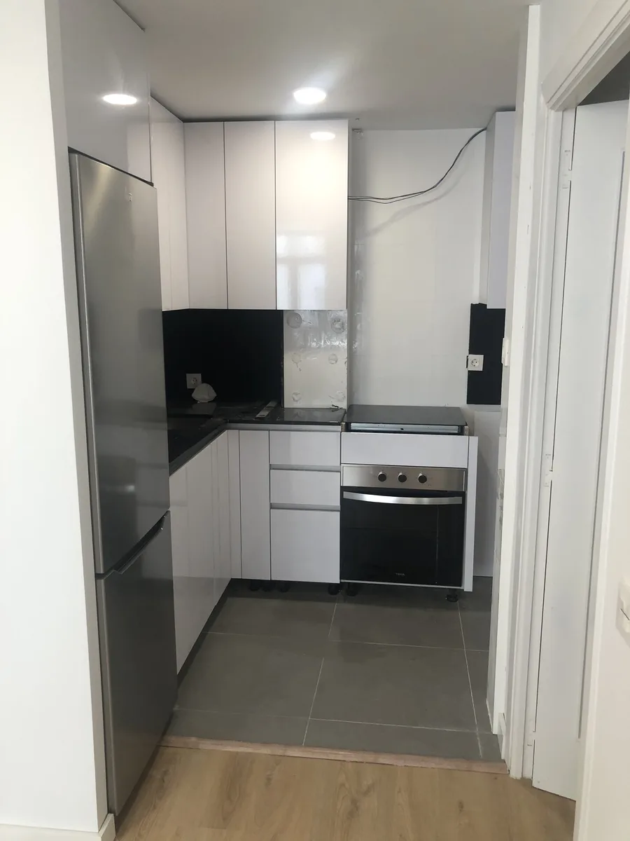 Cocina blanca con muebles altos, horno integrado y encimera oscura