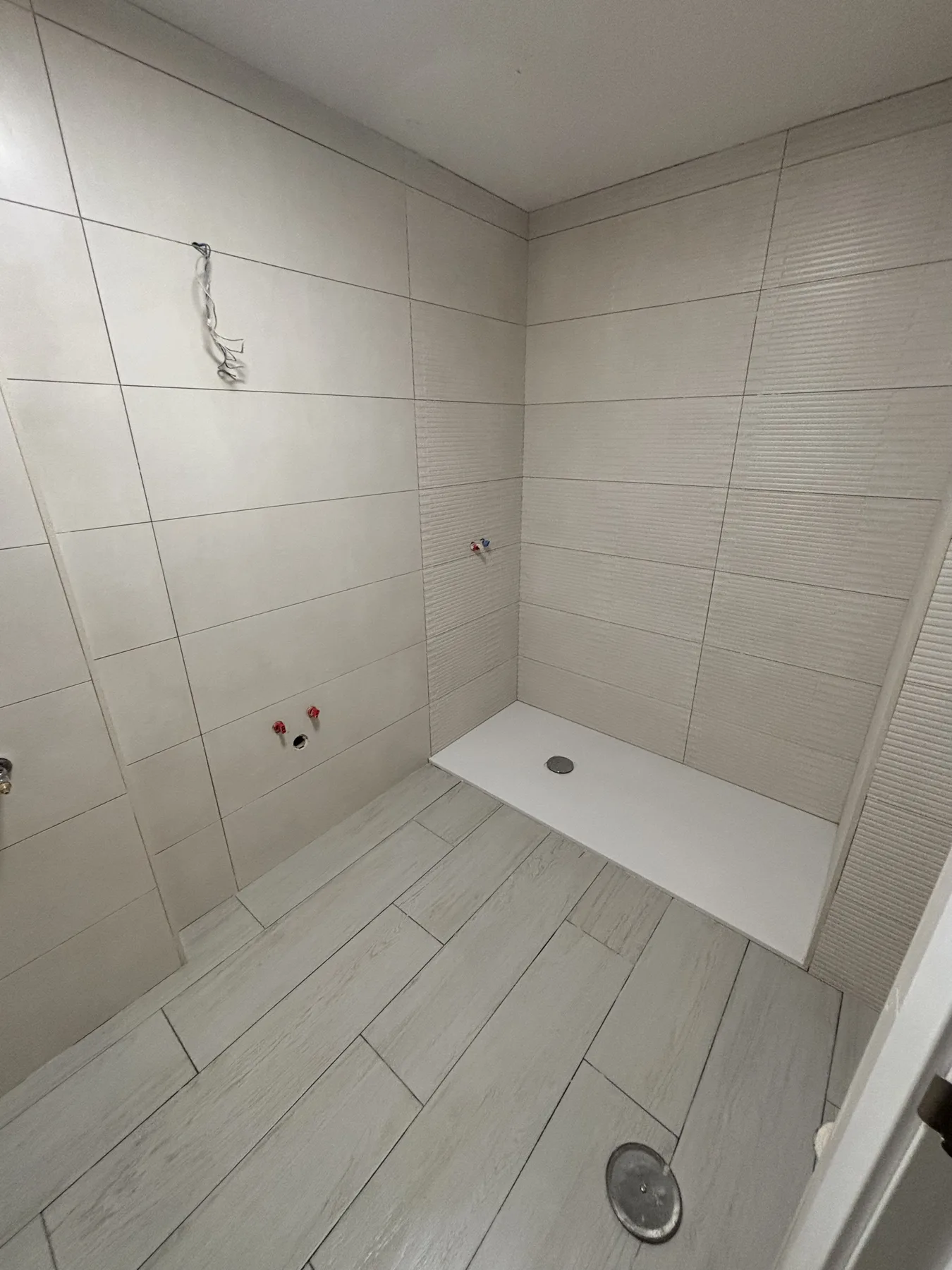Zona de ducha alicatada en blanco con plato de ducha