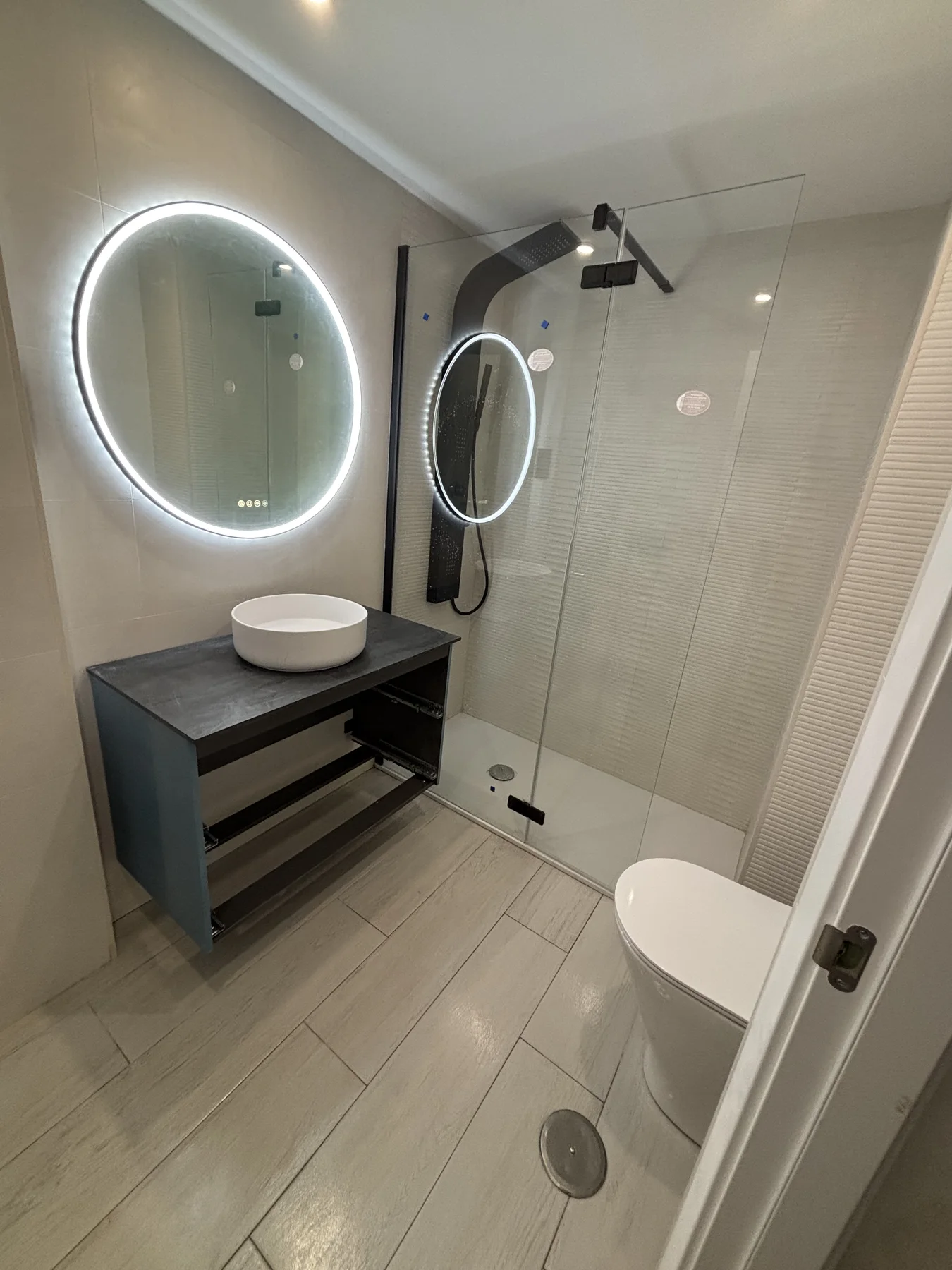 Baño renovado con ducha de obra y espejo iluminado
