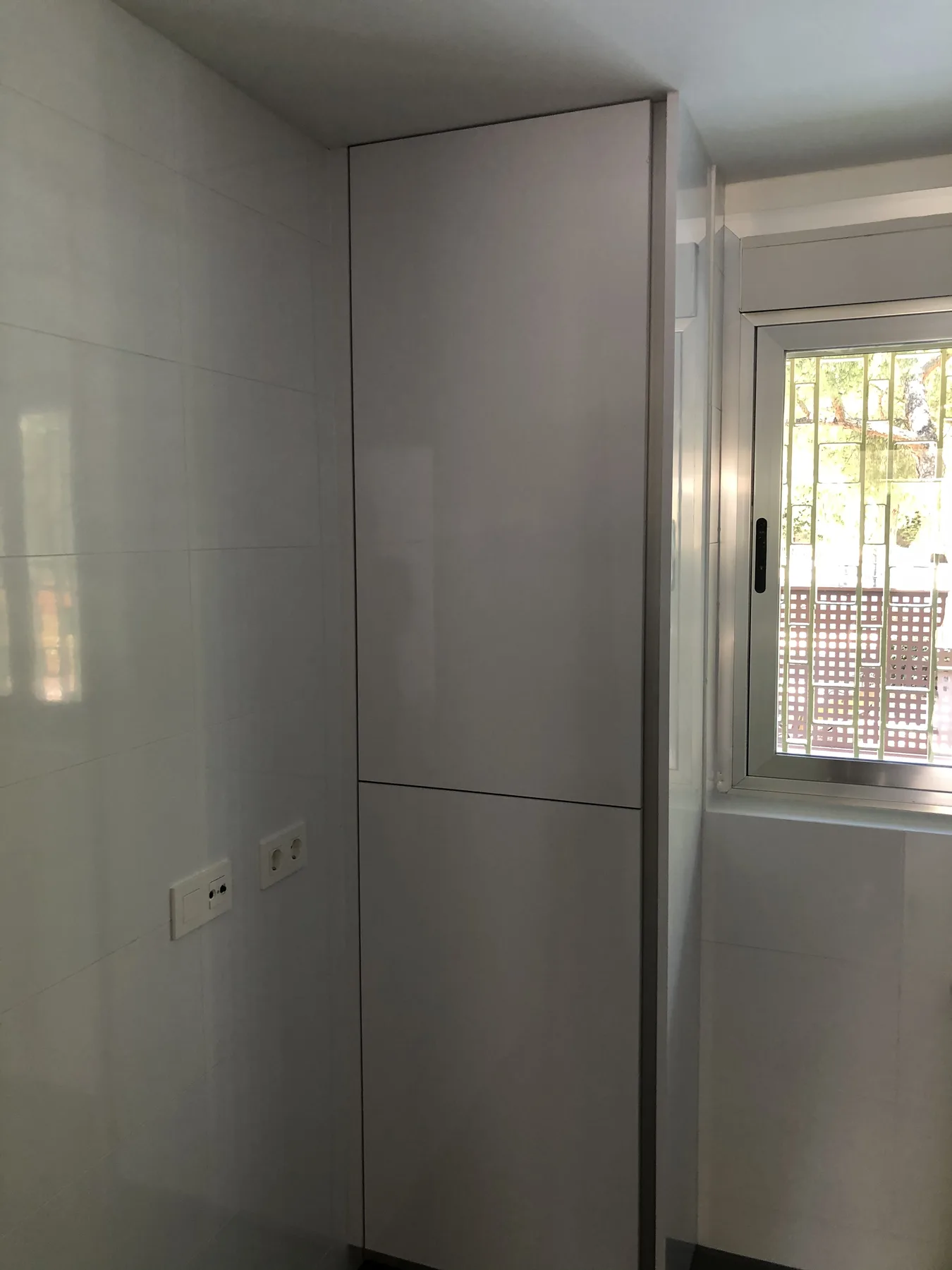 Cocina lineal reformada con muebles blancos y electrodomésticos integrados