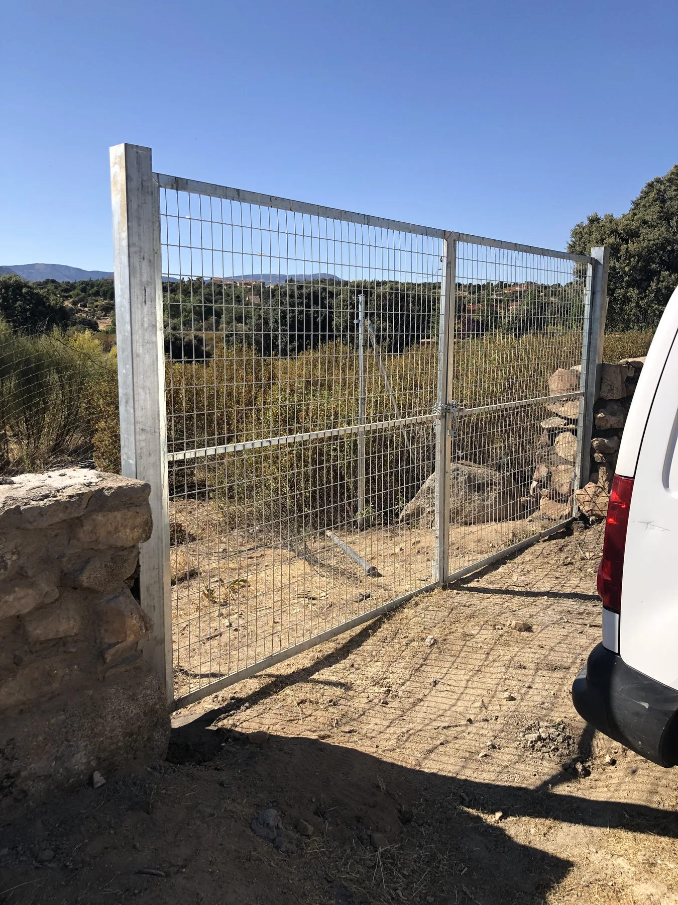 Puerta de doble hoja con panel metálico junto a muro de piedra