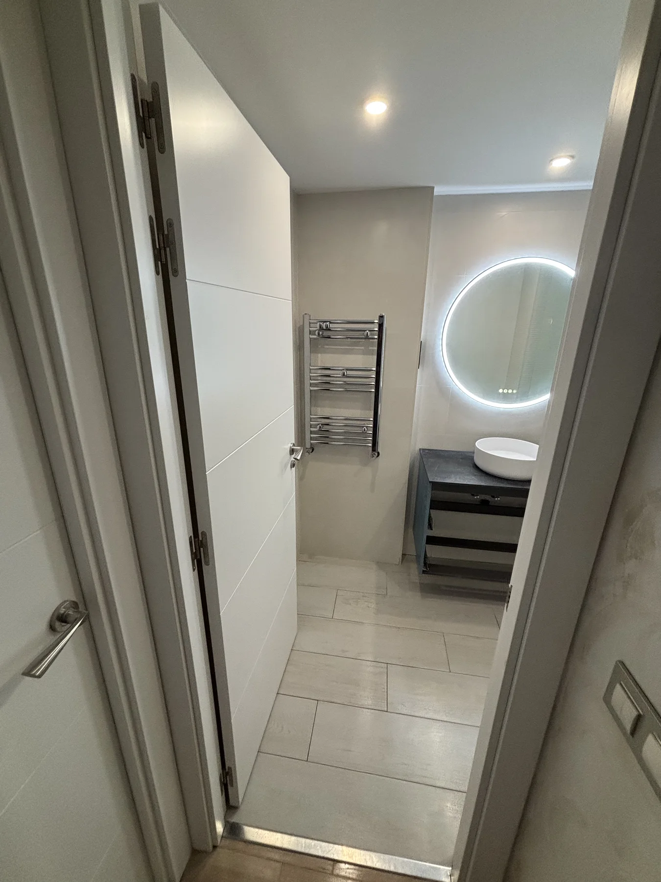 Baño reformado con lavabo sobre encimera y toallero