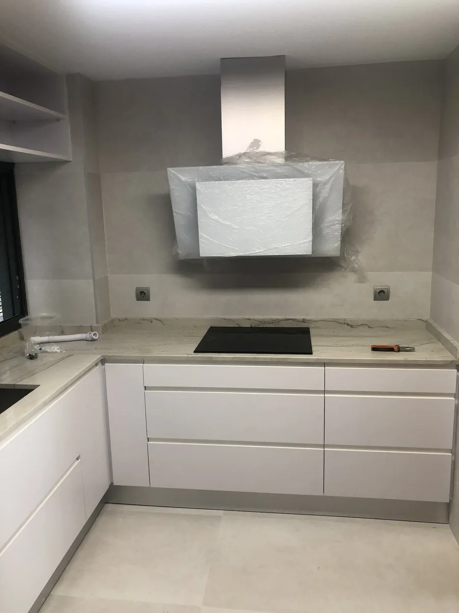 Cocina blanca en esquina con placa de cocción y campana extractora